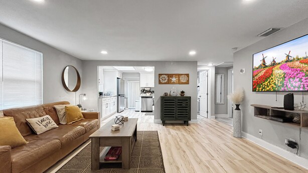 A modern living room with a sofa, coffee table, and TV. - La Casita of St. Petersburg near Beaches and Bars! (St. Petersburg)