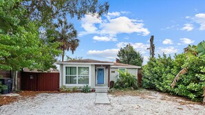 A single-story house with a front porch, a gravel driveway, and a backyard with various plants. - La Casita of St. Petersburg near Beaches and Bars! (St. Petersburg)