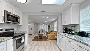 A modern kitchen with stainless steel appliances, white cabinetry, and a skylight. - La Casita of St. Petersburg near Beaches and Bars! (St. Petersburg)