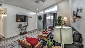 A modern living room with a ceiling fan, a TV mounted on the wall, a dining area with a table and chairs, and a sofa. - ☺ Just Remodeled ☺ 3 Bed / 2 Bath Sparkling Townhouse with Patio! ☺ (Mesa)