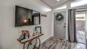 A modern entryway with a mounted TV, a door with a wreath, and a small console table with a bicycle and a sign. - ☺ Just Remodeled ☺ 3 Bed / 2 Bath Sparkling Townhouse with Patio! ☺ (Mesa)