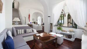 A spacious living room with a staircase, a sofa set, a coffee table, and a bookshelf.
