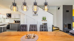 A modern kitchen with white cabinets, a microwave, and a coffee maker. There is a dining area with a wooden table and four chairs. - Modern holiday house JASMINKA (Malinska)