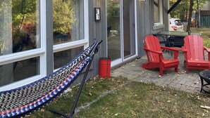 A modern house with large windows, a hammock, and red Adirondack chairs in the backyard. - Forest Chalet Just 5 min to Mt Orford Avail August - December 2026 (Orford)