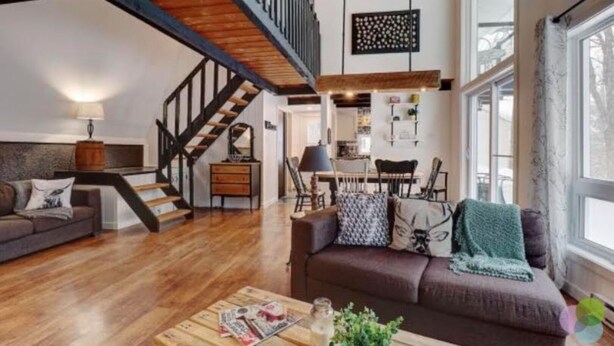 A spacious living room with a wooden staircase, a dining area, and large windows. - Forest Chalet Just 5 min to Mt Orford Avail August - December 2026 (Orford)