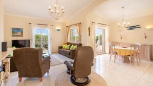 A spacious living area with a sofa, chairs, a dining table, and a television. - Villa Maren, quiet residential area, private pool (Lagos)