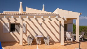 A building with a tiled roof, a chimney, and a covered patio area with a table and chairs. - Villa Maren, quiet residential area, private pool (Lagos)