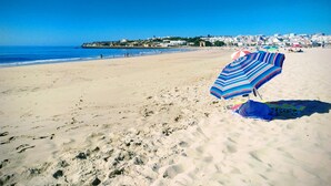 A beach with a striped beach umbrella and a towel on the sand. - Casa Areia Ornata, sea view terrace, beach (Lagos)