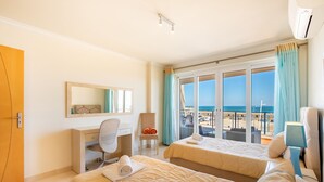 A hotel room with two beds, a desk, a chair, and a large window with a view of the beach. - Casa Areia Ornata, sea view terrace, beach (Lagos)