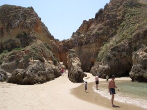 A beach with rocky cliffs and a narrow path leading through the rocks.