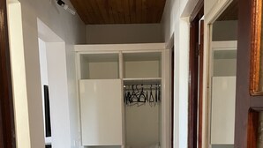 En walk-in-garderob med öppna dörrar, en klädstång och ett kaklat golv.