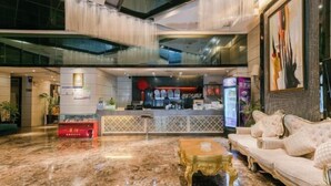 Un vestíbulo con piso de mármol, una recepción, un sofá y una mesa de centro.