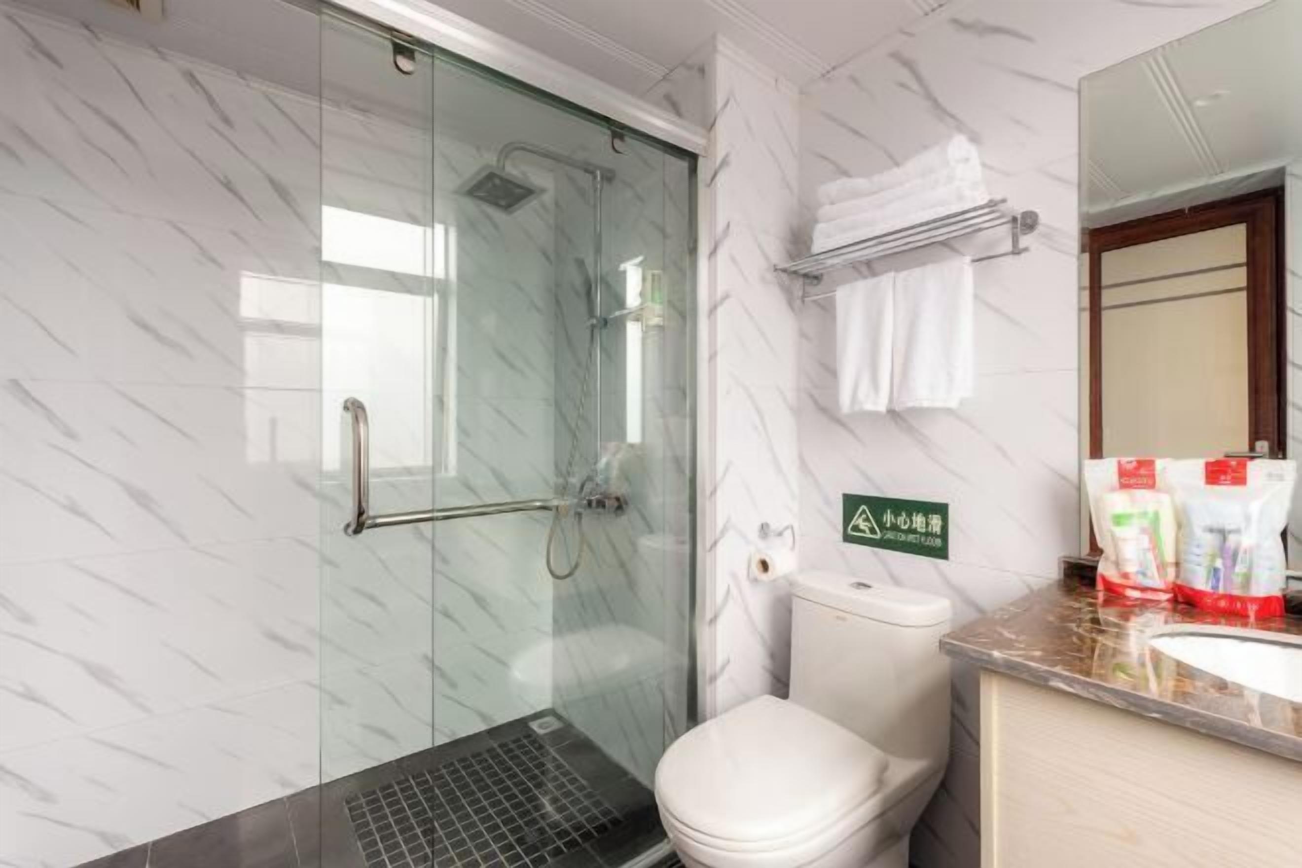 Un baño moderno con ducha envuelta en vidrio, inodoro y lavabo con encimera de mármol.