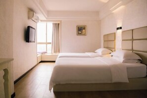 Een hotelkamer met twee bedden, een raam met gordijnen, een schilderij aan de muur en een wandtelevisie.