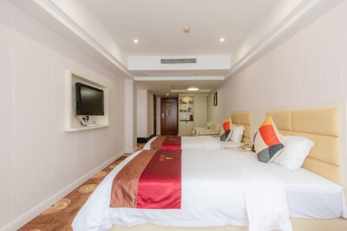 Een hotelkamer met twee bedden, een televisie en een gang naar een badkamer.