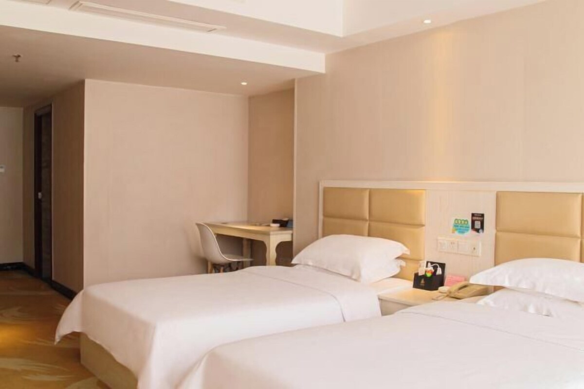 Een hotelkamer met twee bedden, een bureau en een stoel.