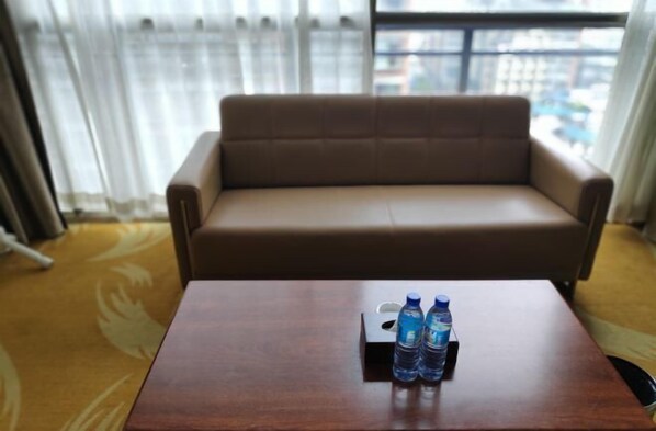 Een kamer met een bruine bank en een houten tafel met twee waterflessen.