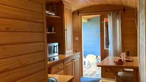 A wooden interior with a kitchen area, including a microwave, sink, and wooden cabinets. - 1 bedroom nice (sta)caravan in Gommenec h (Gommenec h)