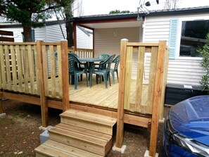 A wooden deck with a table and chairs, leading to a covered patio area.