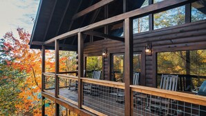 Eine Holzterrasse mit Geländer, mit Blick auf ein bewaldetes Gebiet im Herbstlaub.