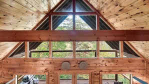 Eine Holzhütte mit einem Giebeldach, großen Fenstern und einer Terrassenfläche.
