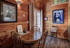 A wooden interior with a round dining table, chairs, a framed picture of a bear, and a framed picture of a bear on the wall. - Hottub* Great Location 3.5 Miles Gatlinburg (Gatlinburg)