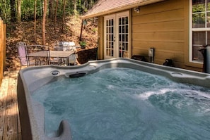 Ein Whirlpool in einem Garten mit einer Holzterrasse, einem Tisch und Stühlen.