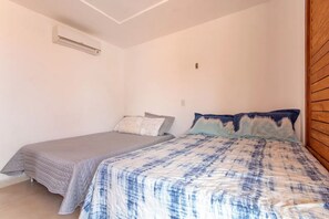 Una camera da letto con due letti, una testiera in legno e un condizionatore d'aria a soffitto.