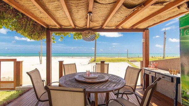 A covered outdoor seating area with a view of the beach.