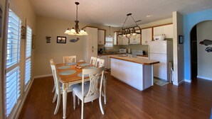 Una cocina moderna con una isla central, armarios blancos e iluminación colgante.