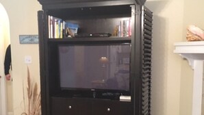 Un mueble multimedia negro con un televisor de pantalla plana, una estantería y un archivador pequeño.