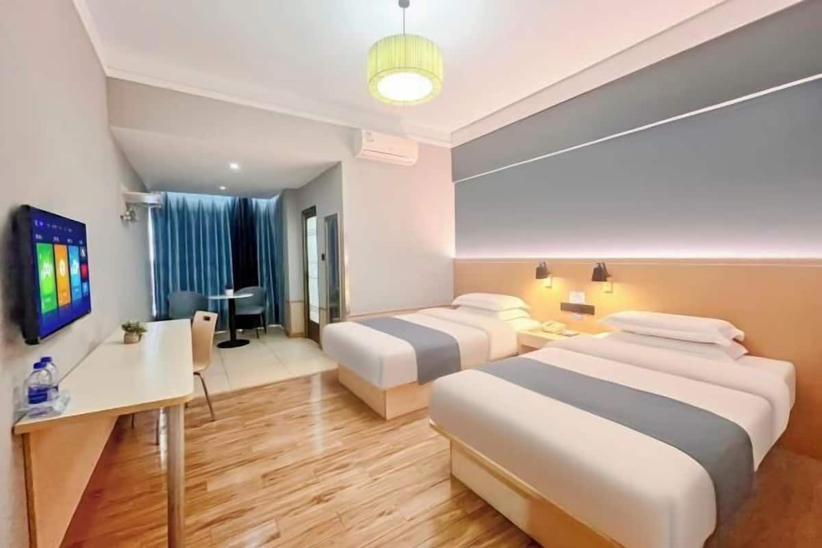 Une chambre d’hôtel avec deux lits, un bureau, une télévision et un luminaire au plafond.