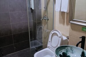 A bathroom with a toilet, a shower, and a sink.