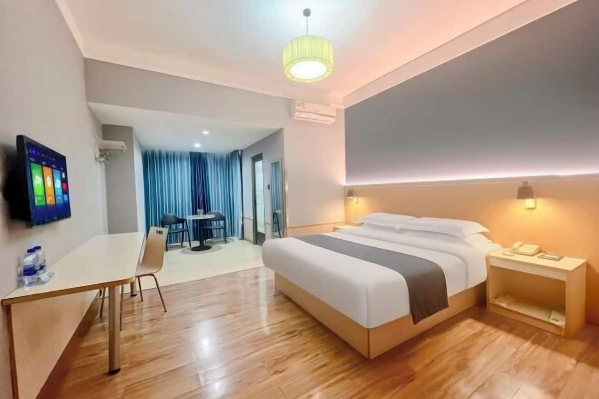 Une chambre d’hôtel comprenant un lit, une table de chevet, un bureau, une chaise et un téléviseur.