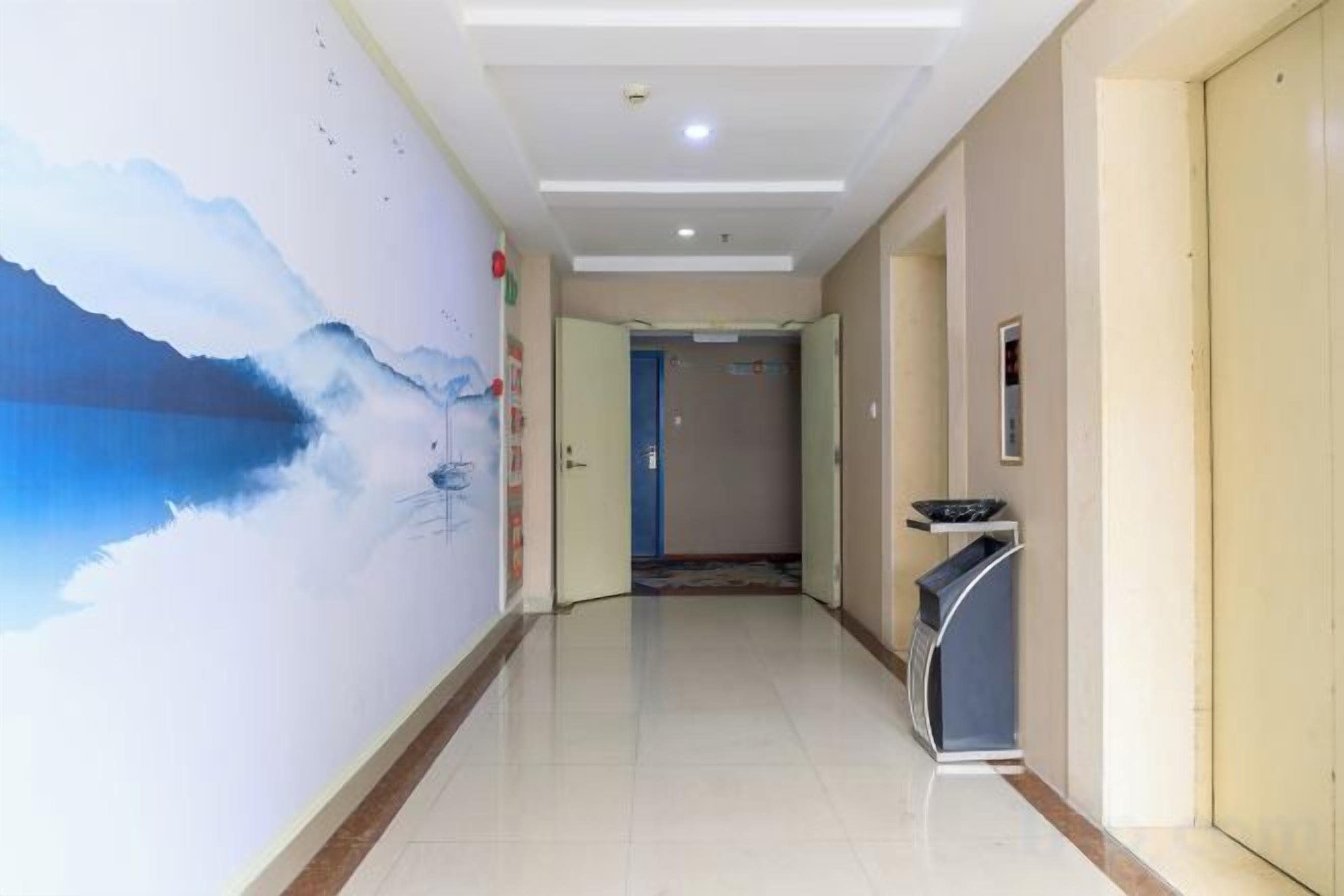 A hotel hallway with a mural, a reception desk, and a door leading to another room.