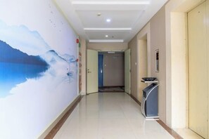 Un couloir d’hôtel orné d’une fresque murale, avec un comptoir de réception et une porte donnant sur une autre pièce.