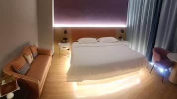 Una habitación de hotel con cama, sofá, una mesita y una silla.