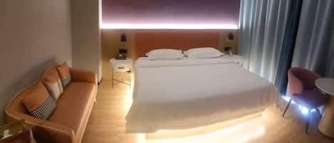 A hotel room with a bed, a sofa, a small table, and a chair.