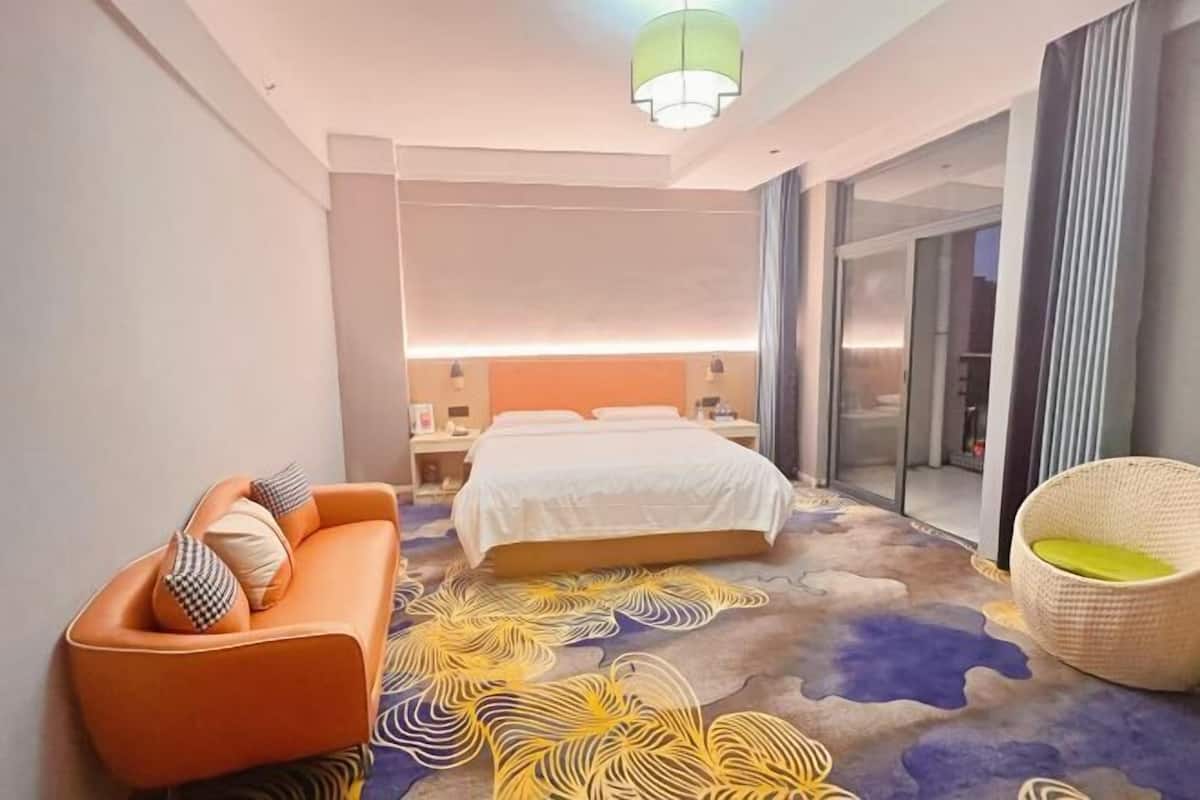 Une chambre d’hôtel moderne, équipée d’un lit, d’un canapé et d’un fauteuil.