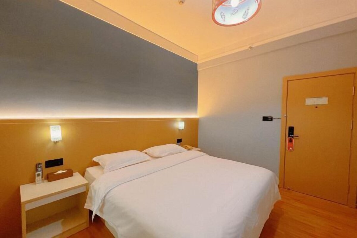 A hotel room with a bed, bedside table, and a door.
