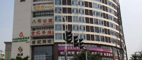Un immeuble à plusieurs étages, doté d’enseignes commerciales, d’un feu de signalisation et d’un lampadaire.
