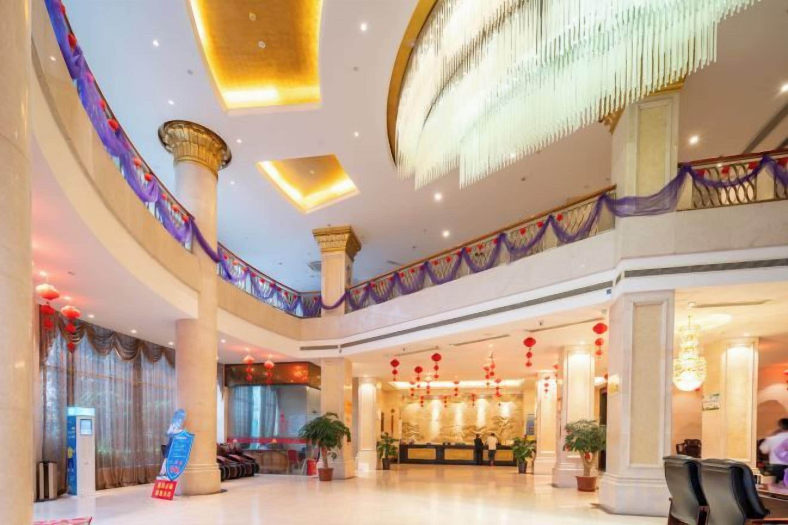 A spacious lobby with a grand chandelier, a reception desk, and a seating area.