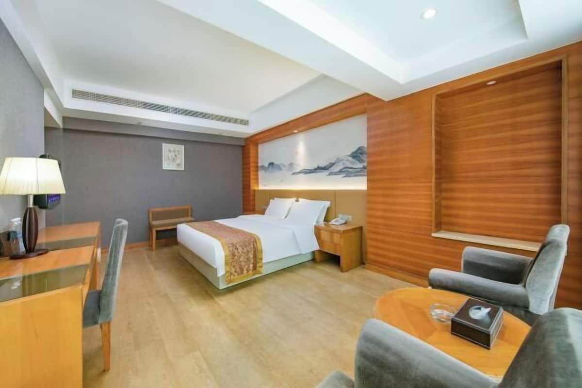 Habitación de hotel con cama, escritorio, sillón, sofá y un cuadro en la pared.