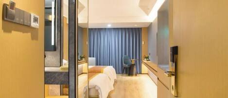 Habitación de hotel con cama, escritorio, silla, espejo y televisor.