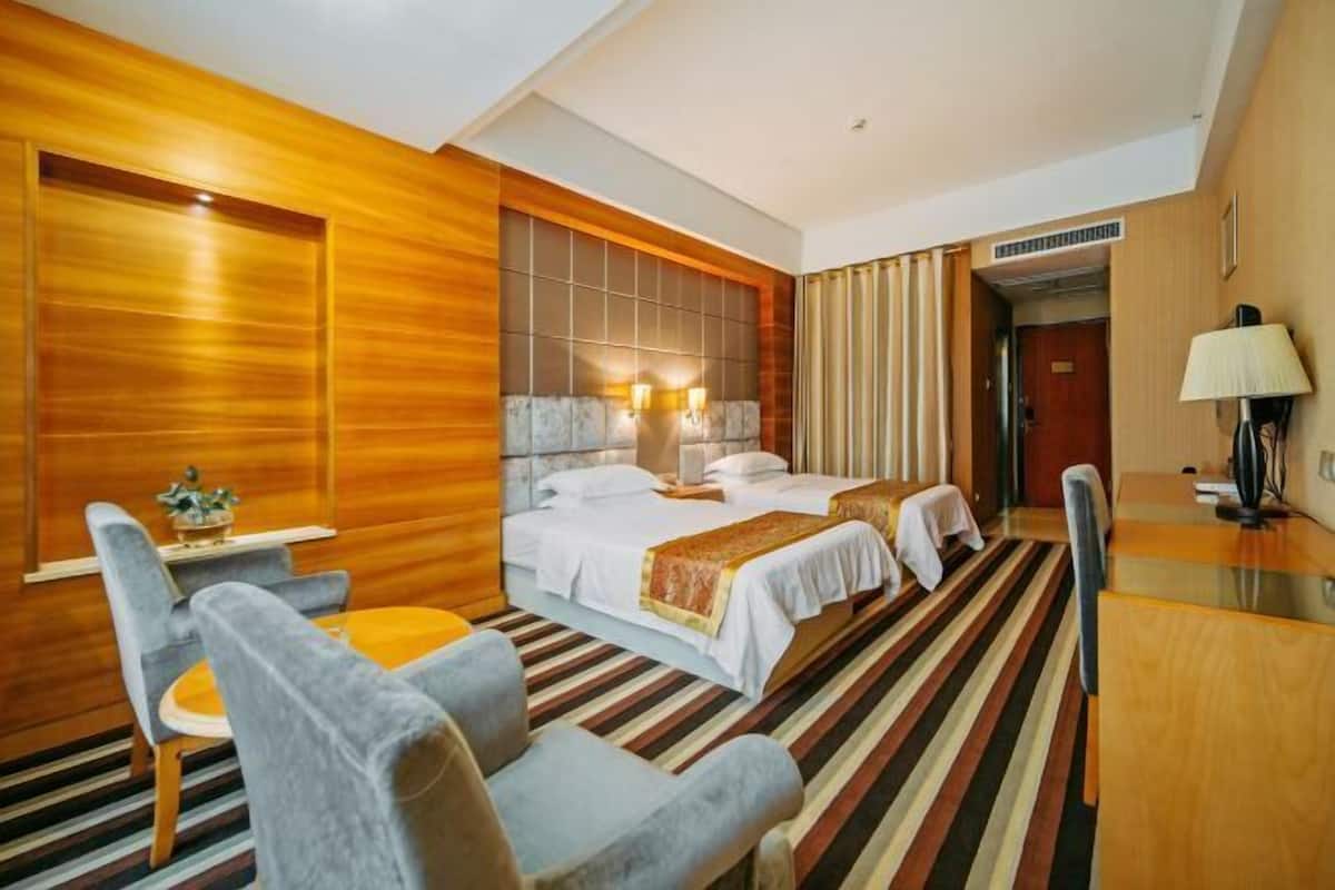 Una habitación de hotel con una cama grande, dos mesitas de noche, un escritorio y una silla.
