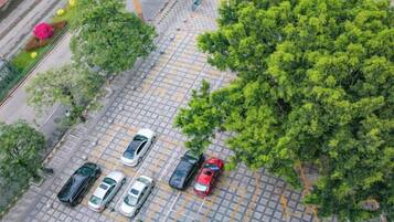 An aerial view of a parking lot with several cars and trees.
