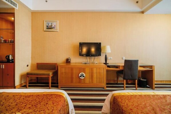 Una habitación de hotel con cama, escritorio, silla, televisor y armario.
