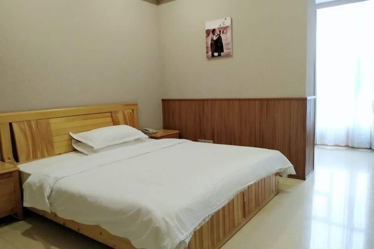 Uma cama bem arrumada com roupa de cama branca, cabeceira de madeira e mesa de cabeceira com abajur.