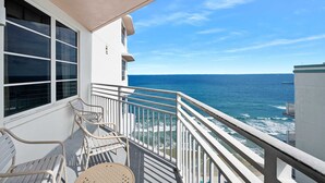 A balcony with white railings, a chair, and a table.