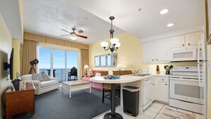 Habitación de hotel con balcón, comedor, cocina y sala de estar.